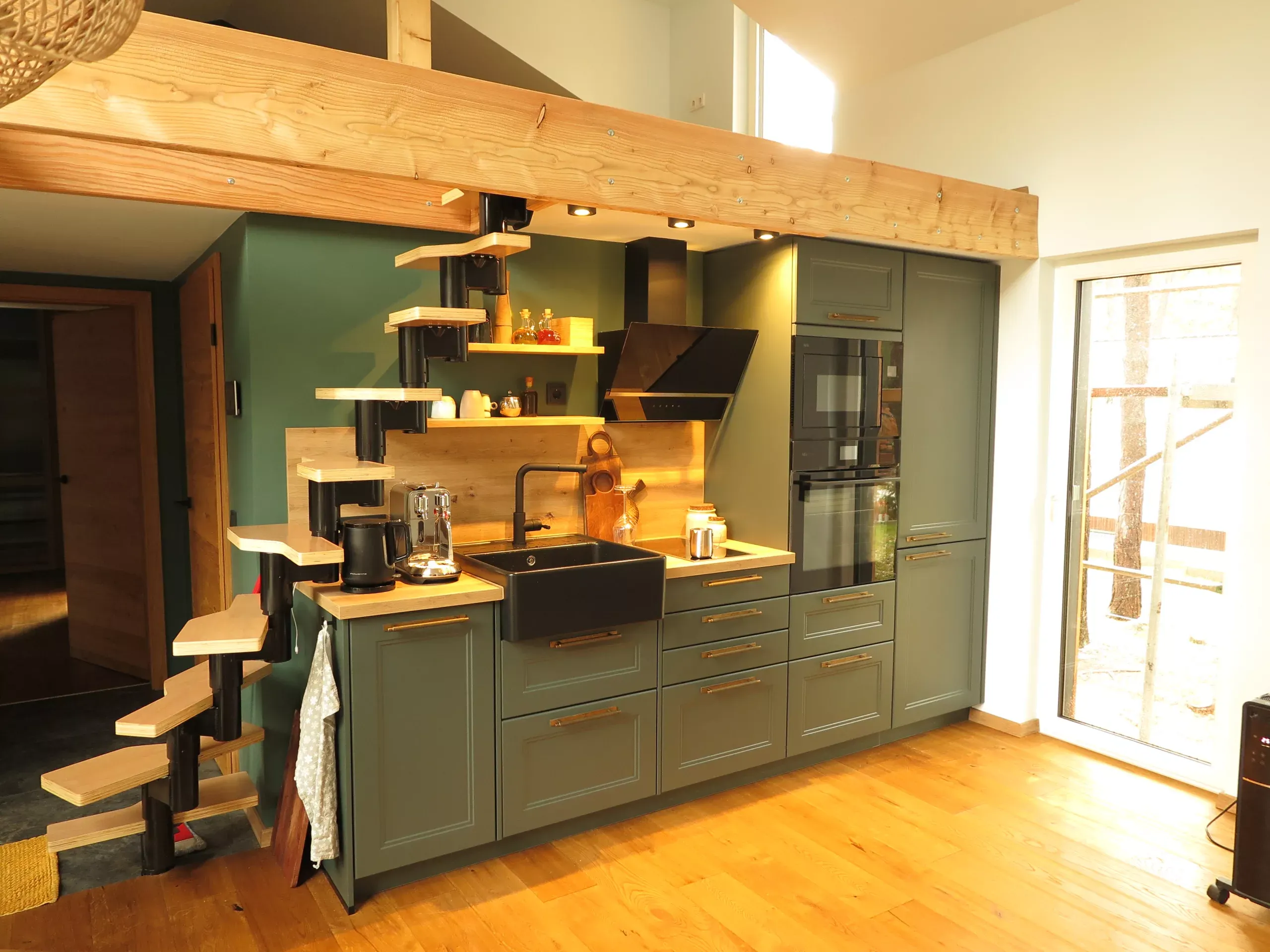 Maßgefertigte Landhausküche in Salbeigrün mit Holz-Arbeitsplatte und schwebender Holztreppe